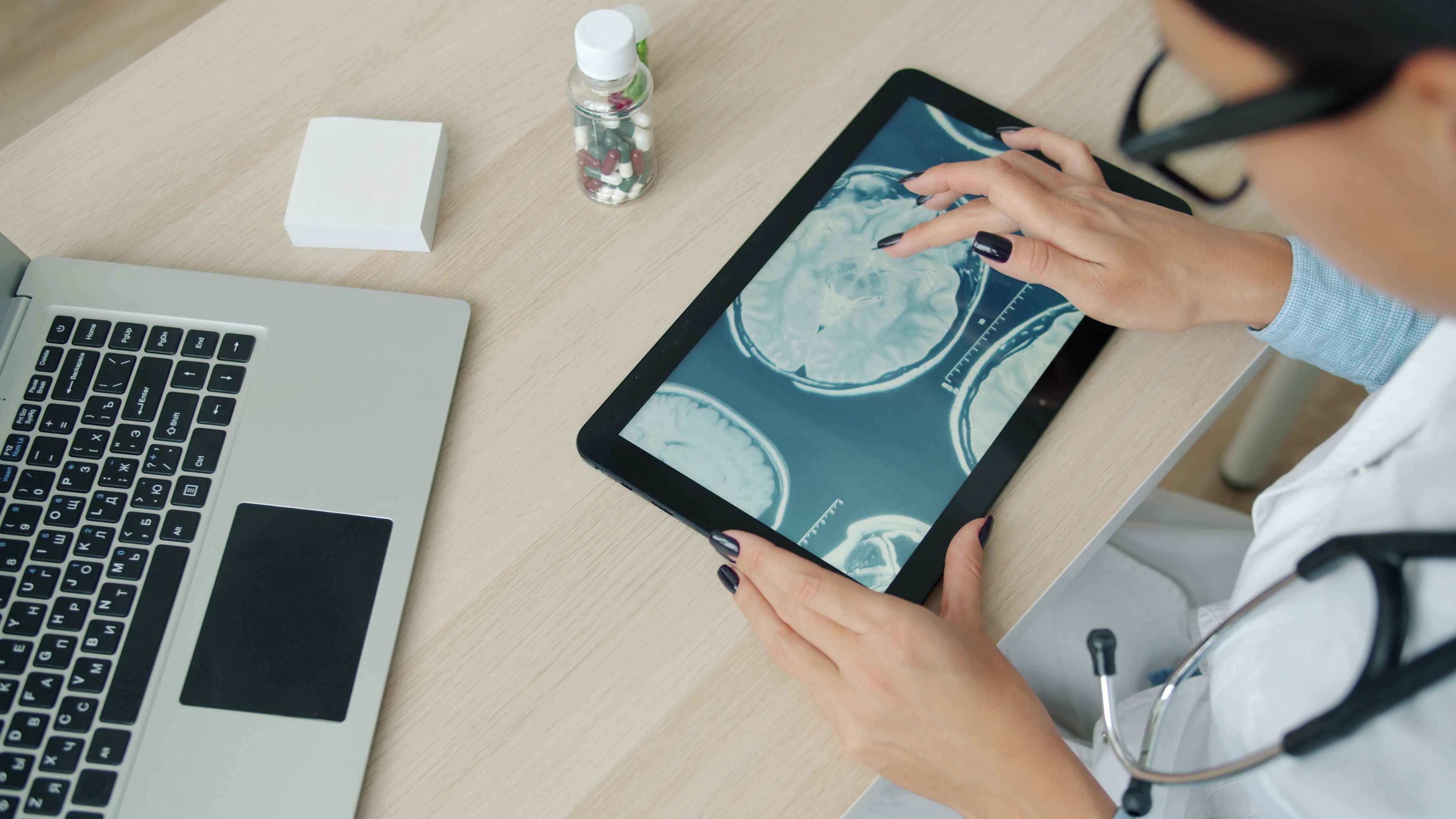 Profissional de saúde observa imagens de ressonância magnética em um tablet.